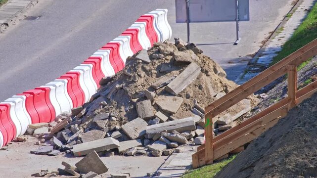 Roadworks Site with Pile of Concrete and Asphalt Rubble on Street Lane Secured with Plastic Safety Barrier