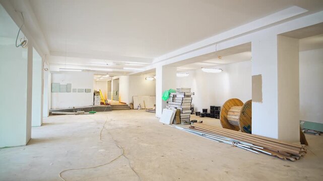 Various construction materials in empty brightly lit hall with large columns. Modern office building interior design development process