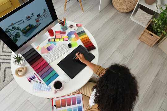 Female African-American interior designer working with graphic tablet at table in office, top view