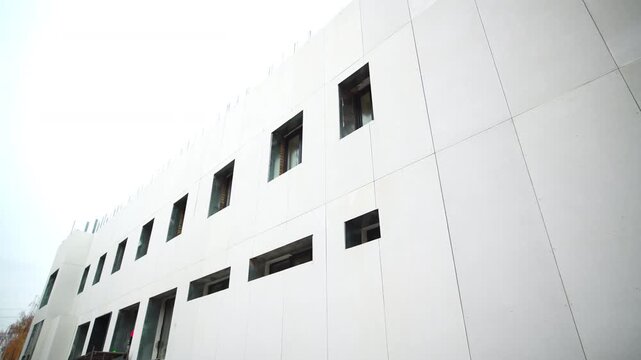 Contemporary commercial building construction site in city block. White facade with windows of new shopping mall in urban environment
