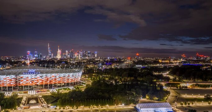 Aerial hyperlapse from National Stadium toward Vistula bridges and Warsaw skyline at blue hour
