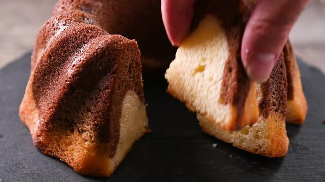 Hand taking a slice of chocolate marble cake
