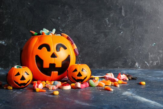 Baskets with different candies for Halloween on dark color table