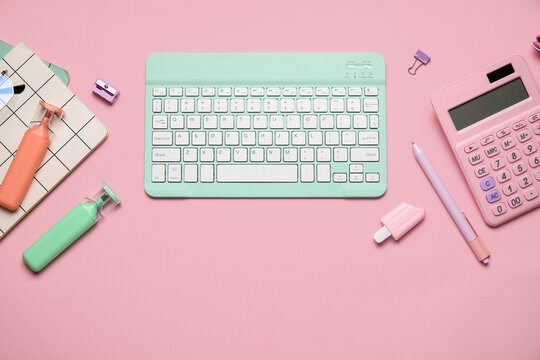 Composition with modern computer keyboard and different stationery on pink background