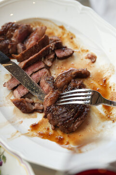Man Cutting Juicy Beef Steak with Glass of Red Wine in Restaurant