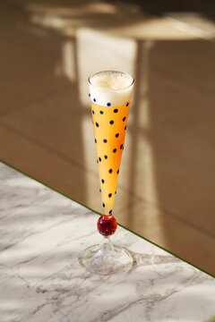 Orange Sparkling Cocktail in Polka Dot Flute on Marble Terrace Table
