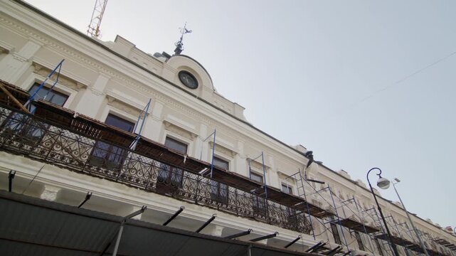 Reconstruction of old classic style building with modern technology in city. Scaffolds placed on facade of vintage architectural landmark