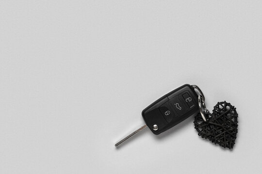 Car key with heart shaped keychain on light background