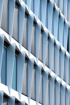 White modern facade with repetitive fins and windows creating an abstract architectural pattern of geometry lines and urban minimalism