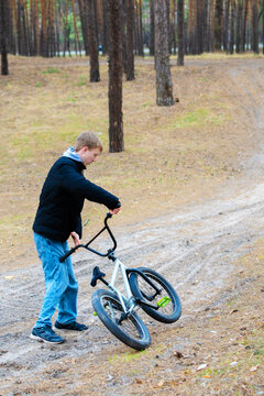 Young man riding a bmx bike on a dirt path in a pine forest outdoor recreation