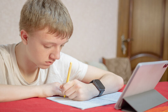 Teenage Boy Studying at Home with Tablet and Notebook for E-learning