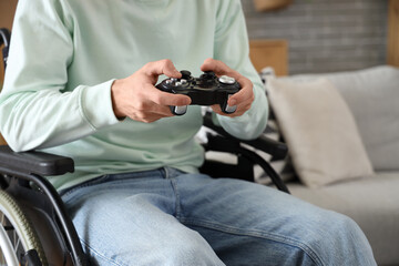 Obraz premium Young man in wheelchair playing video game at home, closeup