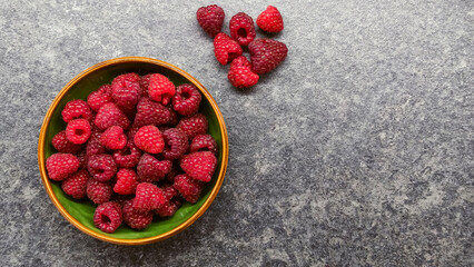 Top view of raspberries in ceramic bowl on stone background © Анатолий Еремин