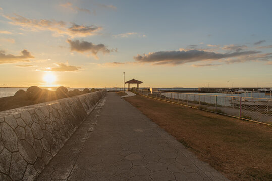オレンジ色の夕暮れの空と東家のある防波堤