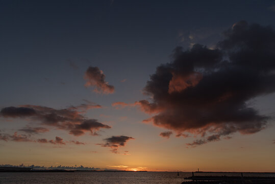 オレンジ色の夕暮れの空とシルエットの防波堤
