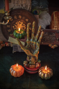 Vintage palmistry hand sculpture with astrological symbols on mystical altar with burning candles for divination