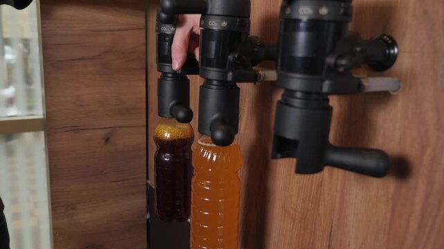 The bartender fills a plastic bottle with freshly brewed craft beer. The beer is served on tap. A man is bottling beer. A process for bottling fresh beer using machinery.