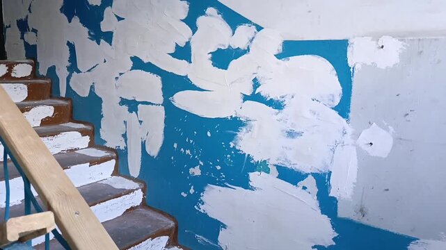 Repaired and plastered wall on a staircase landing in an apartment building entrance, symbolizing construction work, interior renovation, wall restoration and finishing work.
