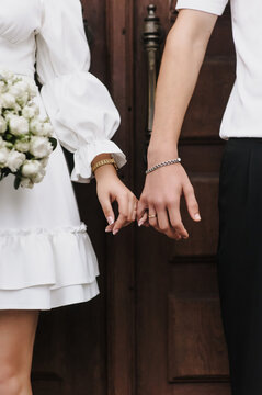 Close-up wedding photo of newlyweds, bride and groom holding hands.