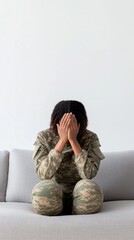 Obraz premium A black female soldier sits on a couch, covering her face with her hands, reflecting on the struggles of military life and mental health