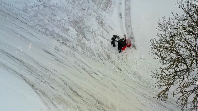 Two people using a red snowblower to remove fresh snow from a path during a winter storm