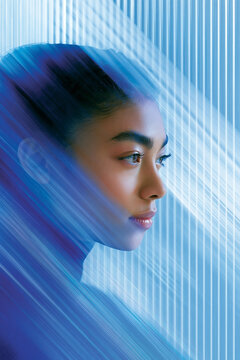 Asian female model with smooth skin and dark hair poses against a blue abstract background featuring vertical lines and soft motion blur effects