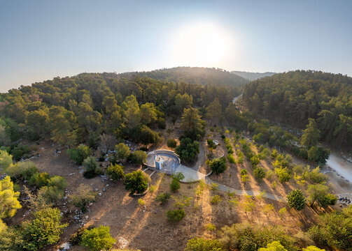 Aerial view of Jerusalem Forest with its circular monument, winding paths, and dense pine trees under the bright sun in Jerusalem, Jerusalem District, Israel.