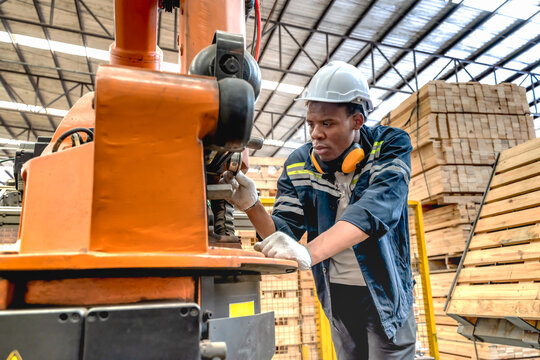 Black male machine engineer adjusting control system parameters on a digital interface screen in modern plywood and timber manufacturing plant