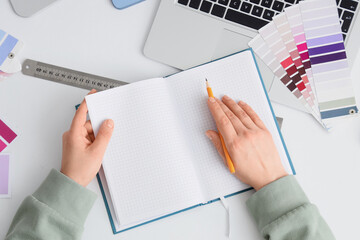 Female interior designers hands with notebook working on table, top view