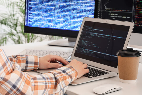 Female programmers hands working with laptop at desk in office, closeup