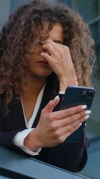 Stressed Caucasian business woman using mobile phone feeling headache eyes discomfort feeling tired near city office building overworked businesswoman female girl agent feel migraine with smartphone