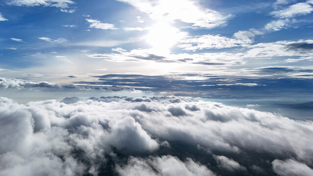 Aerial view of a vast expanse of white clouds illuminated by the bright sun in the blue sky over Sukabumi Regency, West Java, Indonesia.