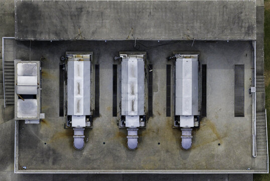 Aerial view of industrial aeration blowers in acoustic enclosures at a wastewater treatment plant with concrete flooring and metal drainage grates in Gallatin, Tennessee, United States.