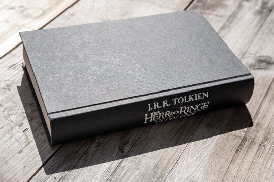 book spine J.R.R. Tolkien, text in German Lord of Rings edition, classic fantasy novel wooden surface, famous fantasy literature, reading hobby with hardcover books, Popular culture bestselling
