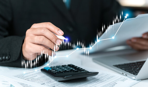 A businessperson is analyzing charts showing financial growth and digital tax obligations&mdash;using a calculator and documents&mdash;to plan investment strategies and achieve success in the stock market.