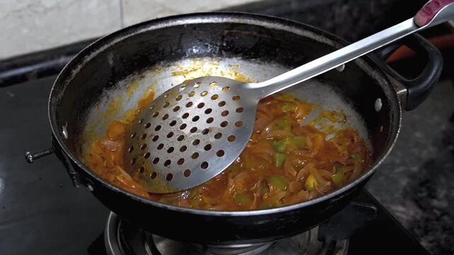 Stir frying chopped onion and capsicum in a pan