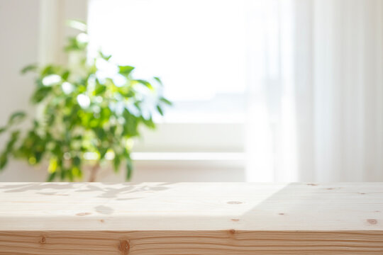 Empty light wooden tabletop with blurred window and green plant as interior background