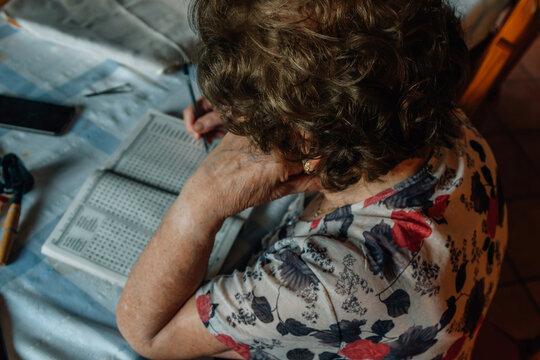senior woman at home writing puzzles or crosswords