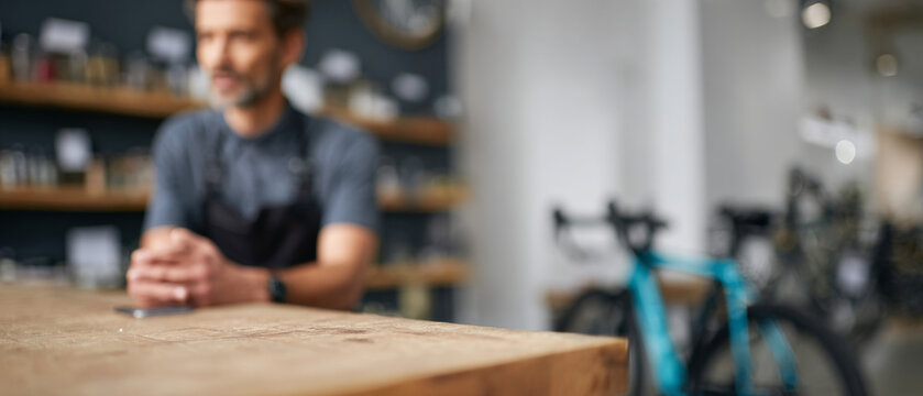 Blurred man behind wooden counter in shop