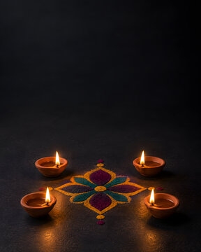 Diwali diyas and rangoli on dark background
