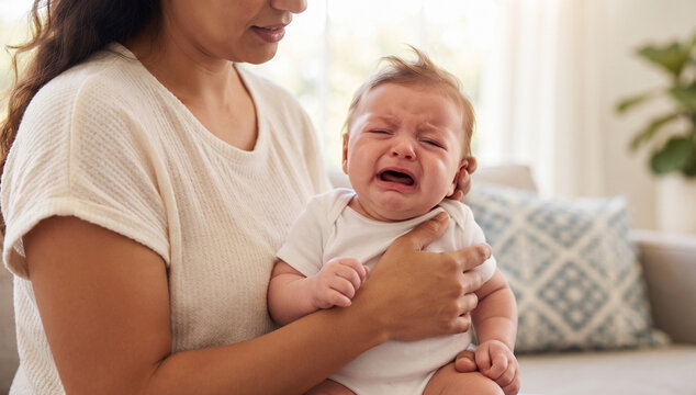 Mother holding and comforting a crying newborn baby at home