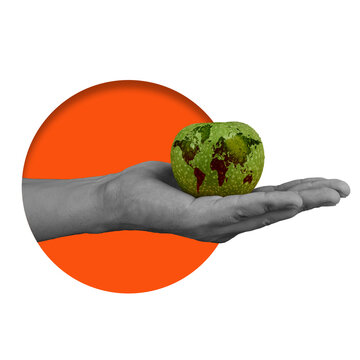 A hand is holding a green apple that has a world map design. The apple sits above a solid orange circle. The scene conveys a message about the Earth and nature.