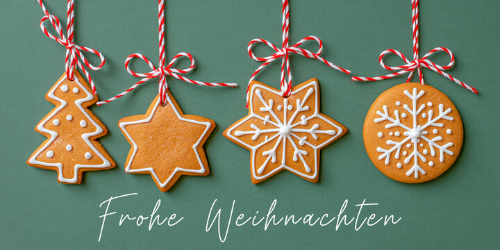 Frohe Weihnachten Gru&szlig;karte, Karte mit deutschem Text - H&auml;ngende weihnachtliche Lebkuchen Keckse Anh&auml;nger, isoliert auf gr&uuml;nem Hintergrund