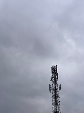 Photography of telecommunication cellular tower against overcast cloudy sky. Connectivity and infrastructure background template for network technology, telecommunication business, and wireless data g