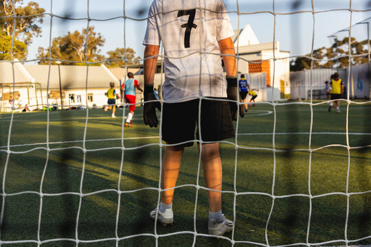 rear view of teenage goalie defending his net at sunset