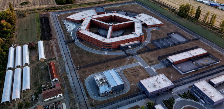 Aerial view of the prison octagon complex with surrounding security fences, agricultural greenhouses, and auxiliary buildings in Pancevo, Serbia.