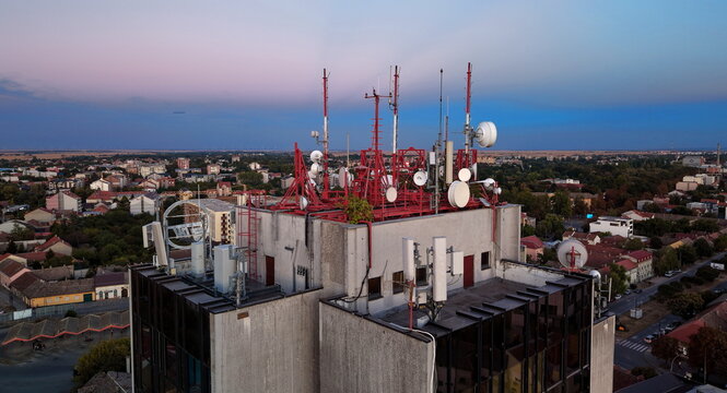 Aerial view of the Main Post Office building featuring numerous red communication towers, antennas, and satellite dishes set against a sunset sky in Pancevo, Serbia.