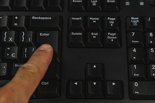 Finger pressing the enter key on a keyboard in an office setting