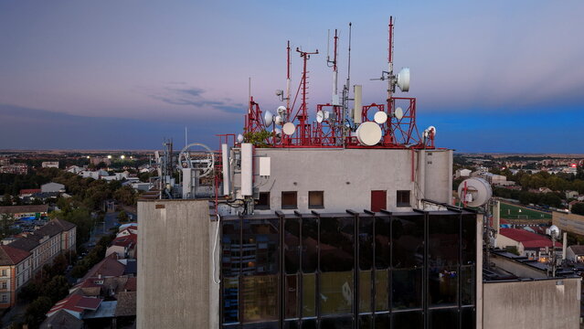 Aerial view of the Main Post Office rooftop featuring numerous telecommunication antennas and satellite dishes against a twilight sky in Pancevo, Serbia.