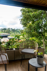 Obraz premium Balcony seating with wicker chairs and potted plants overlooking a green hillside